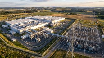 Aerial view of a large data center campus beside electrical substations, transmission lines and rural farmland.