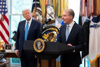 SEC Chairman Paul Atkins speaks at a White House podium as President Donald Trump stands behind him.