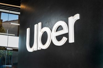 Uber logo mounted on a dark wall outside a building.