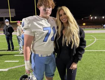 Kroy “KJ” Biermann Jr. and his mother, Kim Zolciak, pose together on a football field.