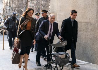 Harvey Weinstein is escorted in a wheelchair by attorneys and officers outside a courthouse.