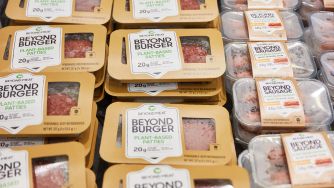 Packages of Beyond Meat plant-based burger patties and sausages arranged in a grocery store display.