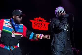 Big Boi and André 3000 perform onstage with an Outkast logo between them.