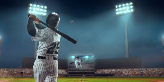 Baseball player in a pinstriped uniform swings a bat under stadium lights.