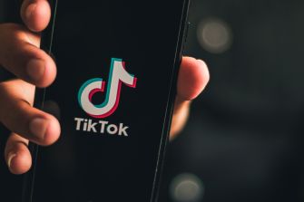 Hand holding a smartphone displaying the TikTok logo.