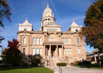Historic courthouse with a domed central tower and two smaller cupolas under a blue sky.