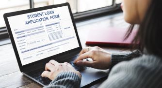 Student fills out a student loan application form on a laptop.