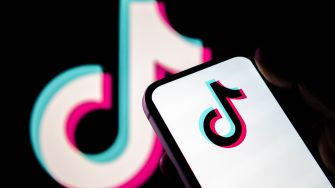 TikTok logo displayed on a smartphone in front of a larger TikTok logo.
