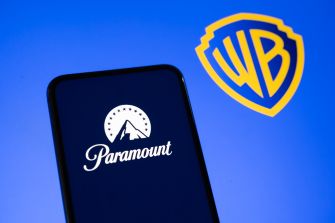 Paramount logo displayed on a smartphone beside the Warner Bros. shield logo.