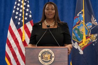 New York Attorney General Letitia James speaks at a podium between the U.S. and New York flags.