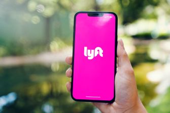 Hand holding a smartphone displaying the Lyft logo.