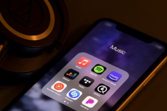 Smartphone displaying a music streaming app folder beside headphones.