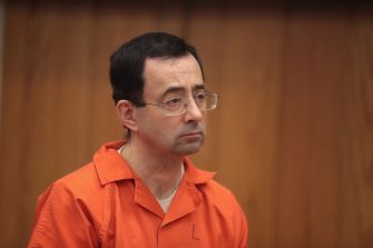 Larry Nassar in an orange prison uniform appears in court.