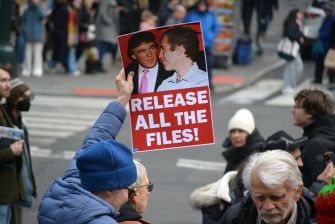 Protester holds a “Release All the Files!” sign featuring Donald Trump and Jeffrey Epstein during a street demonstration.