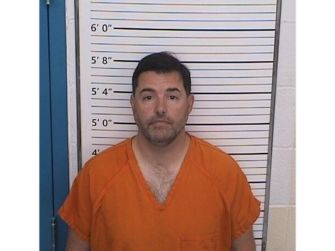 Jed York poses in an orange jail uniform in front of a height-measurement board.