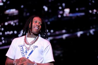 Lil Durk performs onstage wearing a white T-shirt and layered chains.