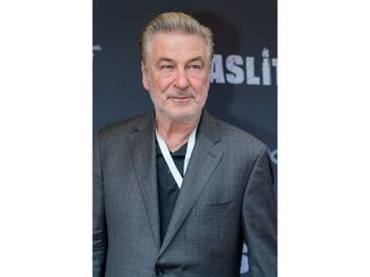 Alec Baldwin poses in a gray suit at a red-carpet event.
