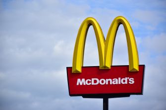 McDonald’s golden arches and red roadside sign against a cloudy blue sky.