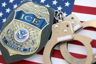 ICE officer badge and handcuffs displayed on an American flag.