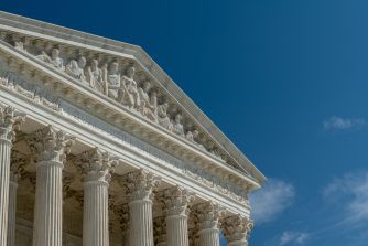 The U.S. Supreme Court building’s neoclassical facade and columns against a blue sky.