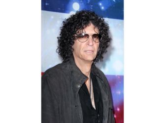 Howard Stern poses wearing sunglasses and a black jacket at a public event.