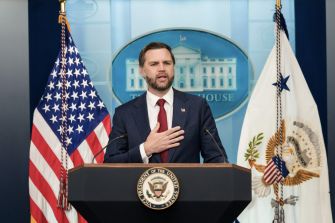 Vice President JD Vance speaks at a White House podium between the U.S. and vice presidential flags.