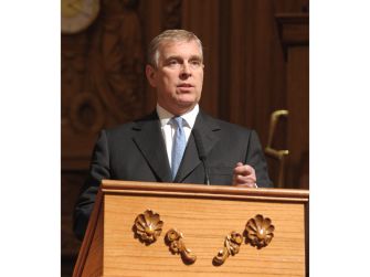 Andrew Mountbatten-Windsor speaks at a wooden podium in a formal interior.
