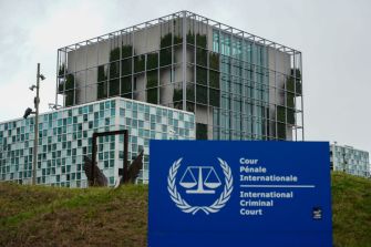International Criminal Court building in The Hague with the court’s blue sign in the foreground.