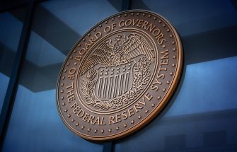 Federal Reserve Board of Governors seal mounted on a blue glass wall.