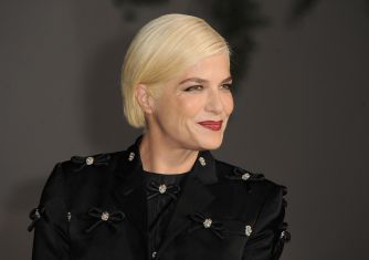 Selma Blair poses in a black embellished jacket against a dark background.