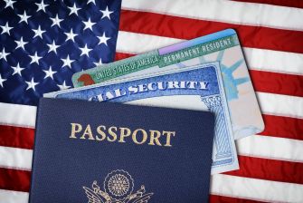 U.S. passport, Social Security card and permanent resident card displayed over an American flag.