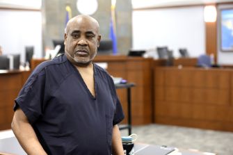 Duane “Keffe D” Davis stands in a courtroom wearing a dark jail uniform.