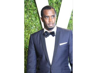 Sean “Diddy” Combs poses in a navy tuxedo with a bow tie at a formal event.