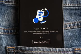 Smartphone displaying a “Sell Tickets” screen resting in the pocket of blue jeans.