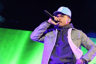 Chance the Rapper, also known as Chancelor Bennett, performs onstage with a microphone.