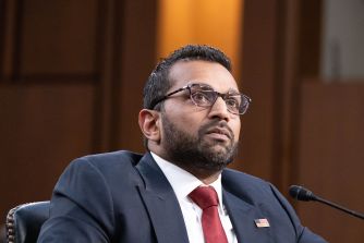FBI Director Kash Patel sits at a hearing table before a microphone.