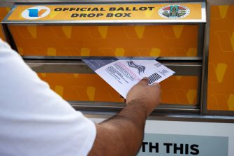 Person placing a ballot into an official ballot drop box.