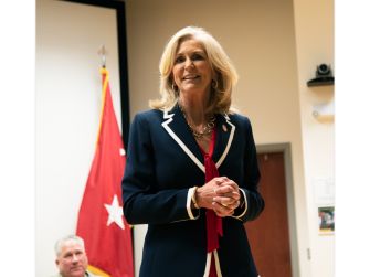 Mississippi Attorney General Lynn Fitch stands with her hands clasped in front of a Mississippi state flag.