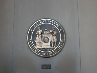 Massachusetts Institute of Technology seal mounted on a gray wall.