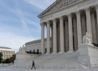 The U.S. Supreme Court building with a person walking across the plaza.