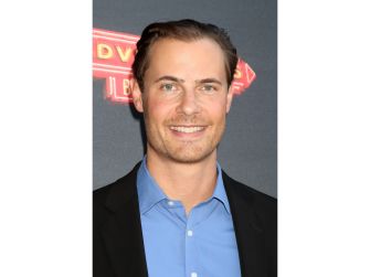 Erik von Detten poses in a black jacket and blue shirt at a red-carpet event.