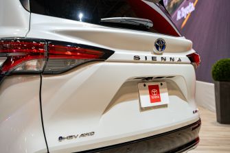 Rear view of a white Toyota Sienna Hybrid minivan displayed indoors.