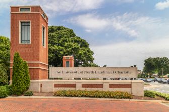 University entrance sign for the University of North Carolina at Charlotte beside a brick campus monument.