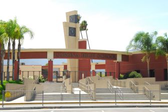 Exterior of Corona High School in Southern California, with palm trees and the school entrance visible.