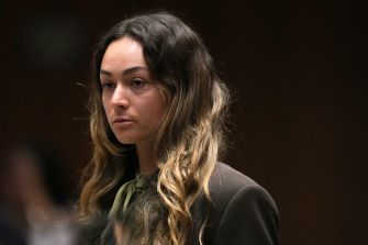 Gabriela “Gabbie” Gonzalez looks to the side in a courtroom, wearing a black jacket and olive-green blouse.