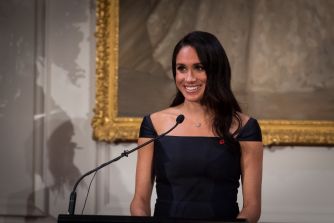 Meghan Markle speaks at a podium in front of a framed painting.