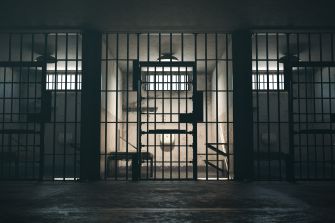Jail cell behind barred doors, illustrating Pooh Shiesty’s reported 23-hour daily isolation while awaiting trial.