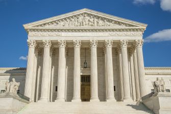 U.S. Supreme Court building with its neoclassical columns and steps beneath a blue sky.