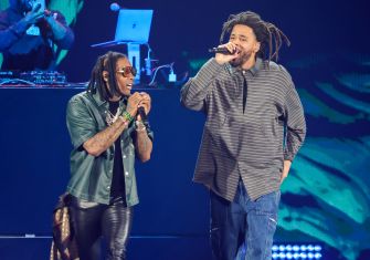 Lil Durk and J. Cole perform together onstage, each holding a microphone.