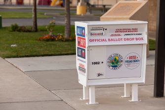 Official ballot drop box labeled for Fresno County on a sidewalk outside a public building.